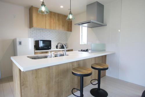 a kitchen with a sink and two bar stools at Hija on the Hill -SEVEN Hotels and Resorts- in Kunigami