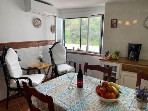un tavolo con un cesto di frutta e una bottiglia di vino di Casa Rural Manantial de las Jaras a Istán