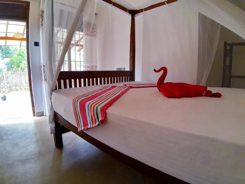 a bedroom with a bed with a red bird on it at Cashew Villa Hiriketiya in Hiriketiya