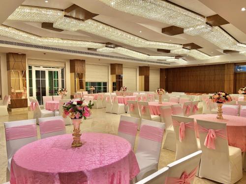 a banquet hall with pink tables and white chairs at SJ PARADISE in Dehradun