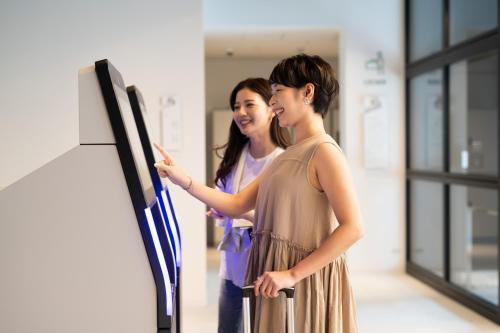 two women are standing in front of a board at Prince Smart Inn Naha in Naha