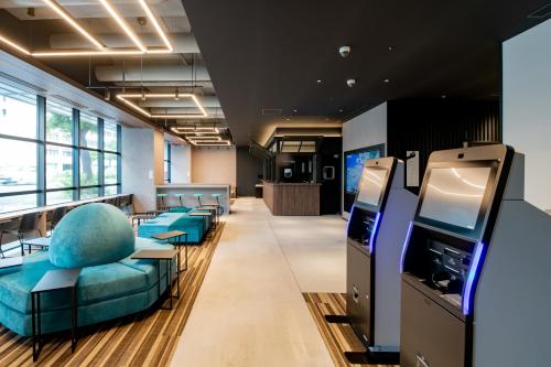 un bureau avec une salle d'attente dotée de chaises bleues et d'une télévision dans l'établissement Prince Smart Inn Naha, à Naha