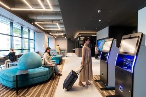 a woman pulling a suitcase in an office with a video game at Prince Smart Inn Naha in Naha