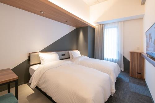 a hotel room with two beds and a tv at Prince Smart Inn Naha in Naha