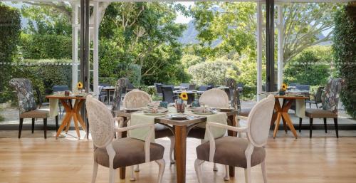 a dining room with tables and chairs and a large window at Vineyard Hotel in Cape Town
