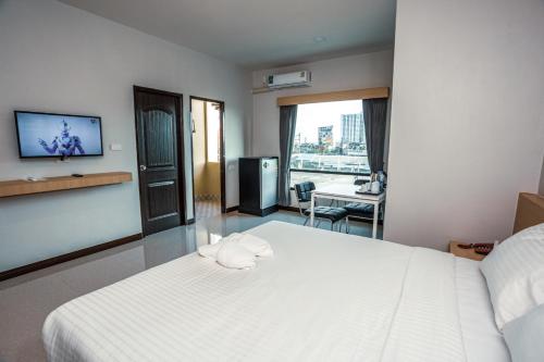 um quarto com uma cama branca e uma televisão na parede em AT Apartment em Hat Yai