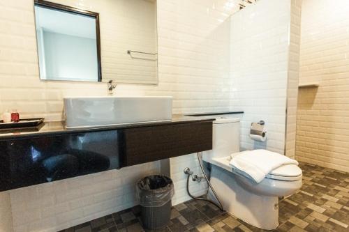 La salle de bains est pourvue de toilettes blanches et d'un lavabo. dans l'établissement AT Apartment, à Hat Yai