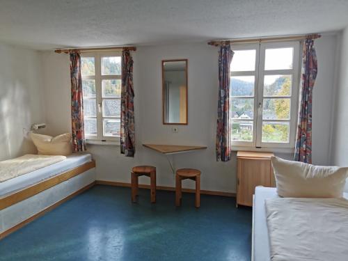 1 Schlafzimmer mit einem Bett, einem Schreibtisch und 2 Fenstern in der Unterkunft Europäisches Gäste- und Seminarhaus in Todtmoos