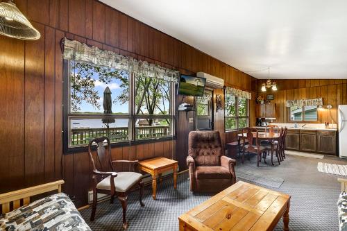 ein Wohnzimmer mit Holzwänden sowie einem Tisch und Stühlen in der Unterkunft Swan Lake Resort & Campground in Fergus Falls