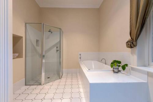 a bathroom with a shower and a tub and a sink at Tanunda Central Cottage in Tanunda