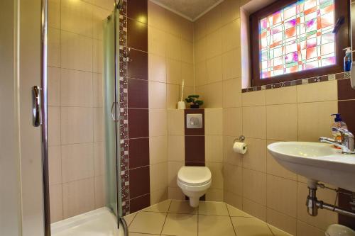 łazienka z toaletą, umywalką i oknem w obiekcie Willa Radosna w mieście Rudzica