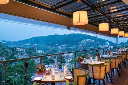 a restaurant with tables and chairs on a balcony with a view at Grand Serendib Hotel in Kandy