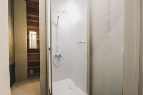 uma casa de banho com um chuveiro e uma porta de vidro em コトリ コワーキング&ホステル高松 em Takamatsu