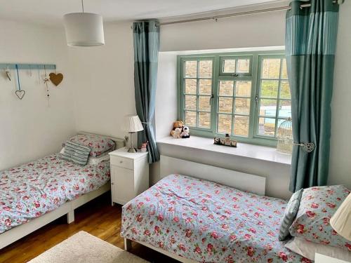 a bedroom with two beds and a window at The Cottage Harmby in Spennithorne