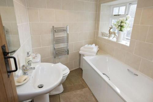 a bathroom with a tub and a toilet and a sink at The Cottage Harmby in Spennithorne