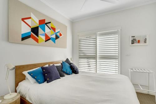 una camera da letto con un grande letto bianco con cuscini blu di Sunchaser at Iluka Resort Apartments a Palm Beach