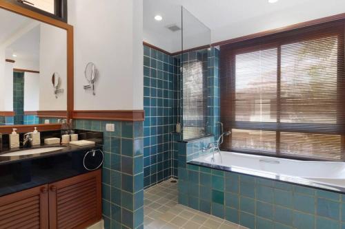 La salle de bains est pourvue de carrelage bleu, d'une baignoire et d'un lavabo. dans l'établissement Laguna Fairway Villa, à Layan Beach