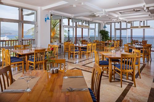 um restaurante com mesas e cadeiras de madeira e janelas em AQI Hydros Club em Kemer