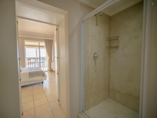 a bathroom with a walk in shower next to a bedroom at 9 Quarter Deck in St Francis Bay
