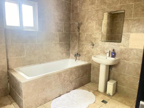 La salle de bains est pourvue d'une baignoire et d'un lavabo. dans l'établissement Luxury @ the Garden, à Accra