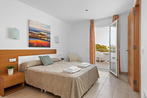 a bedroom with a bed and a sliding glass door at Villas Calan Bosch Ona in Cala en Bosc