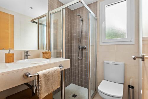 uma casa de banho com um WC, um lavatório e um chuveiro em Villas Calan Bosch Ona em Cala'n Bosch