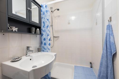La salle de bains blanche est pourvue d'un lavabo et d'une douche. dans l'établissement Infinity Stay Maritim Bis zu 4 Personen Zentrumsnah Netflix, à Wilhelmshaven