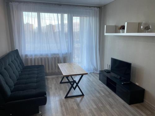 een woonkamer met een bank, een tafel en een televisie bij Krymo g., 1 kambarys in Šiauliai