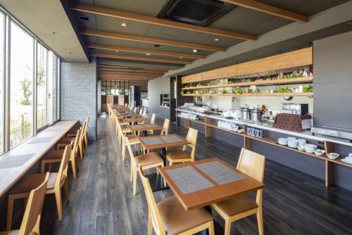 um restaurante com mesas e cadeiras de madeira e uma cozinha em Hotel Grand View Fukuoka-Kuko em Fukuoka