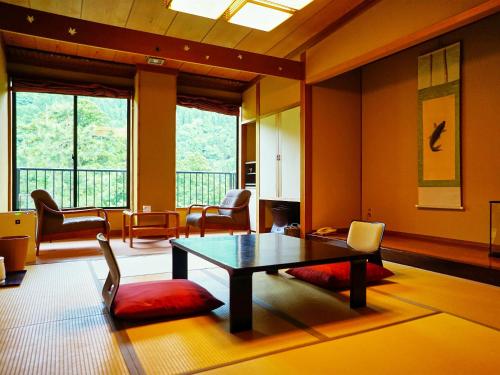 salon ze stołem, krzesłami i oknami w obiekcie Sanrakuen w mieście Tonami