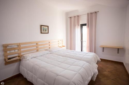 Un dormitorio con una gran cama blanca y una ventana en Hostal Rio en Medellín