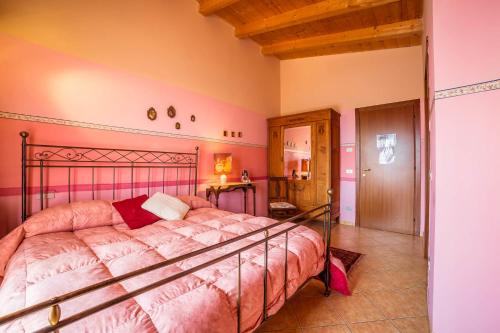 a bedroom with a large bed with pink walls at Le Mistral in Sommacampagna