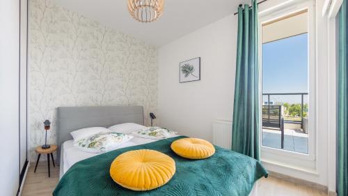 a bedroom with a bed with two orange pillows on it at Apartamenty Sun & Snow Nowe Hallerowo in Władysławowo