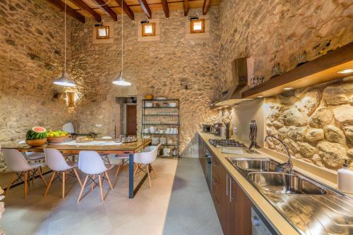 a kitchen with a table and chairs and a stone wall at Sa Serra in Sant Joan