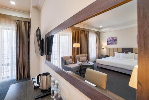 a hotel room with a bed and a large mirror at Ambassador Hotel in Bishkek