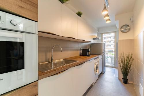 une cuisine avec des armoires blanches et un évier dans l'établissement Le Mistral - Appt avec deux balcons à Cannes, à Cannes