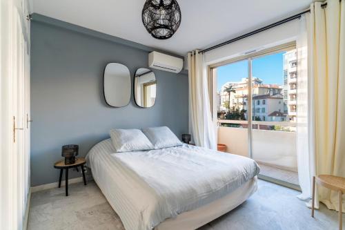 une chambre avec un lit et une grande fenêtre dans l'établissement Le Mistral - Appt avec deux balcons à Cannes, à Cannes