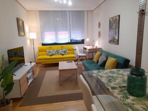 a living room with a yellow couch and a table at Apartamento céntrico con wifi y parking de coche tamaño medio in Cangas de Onís