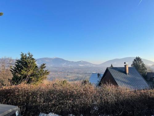 a house on a hill with mountains in the background at Retro chata na Čupku in Metylovice