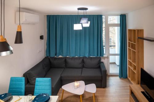 a living room with a black couch and blue chairs at Modern and Cozy 1BDR Apartment in the City Center in Sofia