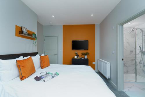 a bedroom with a white bed with an orange wall at Apt Three - Private Car Park - 3 shower rooms - by Ocean City Retreats in Plymouth