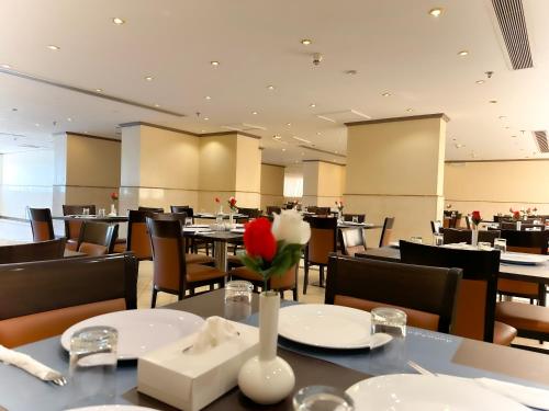 a restaurant with tables and chairs with red and white flowers at Al Massa Bader Hotel in Makkah