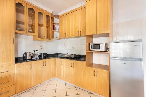 een keuken met houten kasten en een roestvrijstalen koelkast bij North Manor Nakuru in Nakuru
