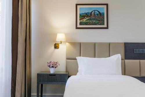 a hotel room with a bed and a table with a lamp at Ambassador Hotel in Bishkek