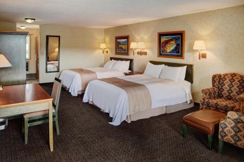 Habitación de hotel con 2 camas, escritorio y silla en Lakeview Inns & Suites - Hinton, en Hinton