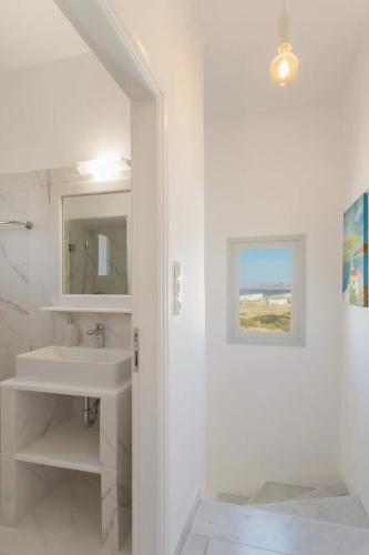 a white bathroom with a sink and a mirror at Maisonette Sail privete pool and sea view in Naousa