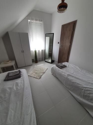 a white bedroom with a bed and a mirror at Sóstó Apartman in Székesfehérvár