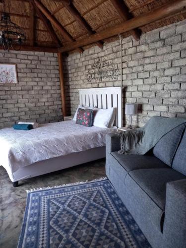 ein Schlafzimmer mit einem Bett, einem Sofa und einer Ziegelwand in der Unterkunft Slypsteen Guest Farm in Sternham