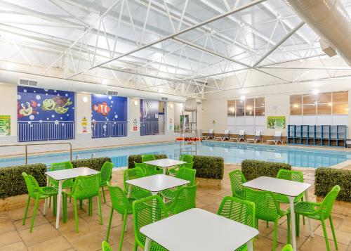 a pool room with tables and chairs and a swimming pool at North Devon Resort in Ilfracombe