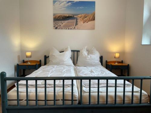 a bedroom with a bed with white sheets and pillows at Strandhaus am Kurpark in Cuxhaven